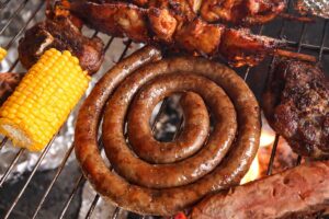 South African braai. Braai including boerewors sausage, lamb chops and chicken kebabs. Including mielie or corn on the cob cooking over charcoal