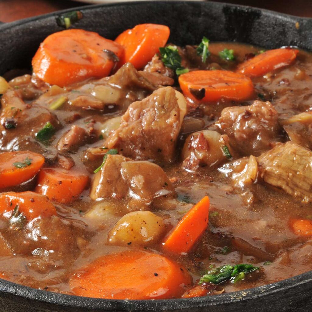 a delicious beef stew in a cast iron pan. Large chunks of tender beef and sliced carrots in a rich gravy!